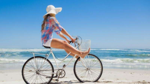 Hilton Head Exclusives. a woman on a bike on a beach