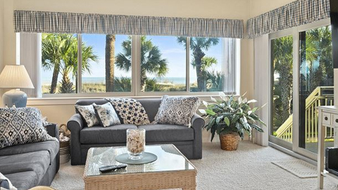 Captains Walk 403. a living room with two blue-gray sofas, a glass-topped coffee table