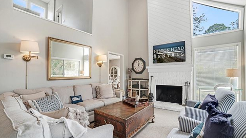 Gadwall 3. a living room with high ceilings, a fire place, a sectional sofa and 2 blue striped chairs